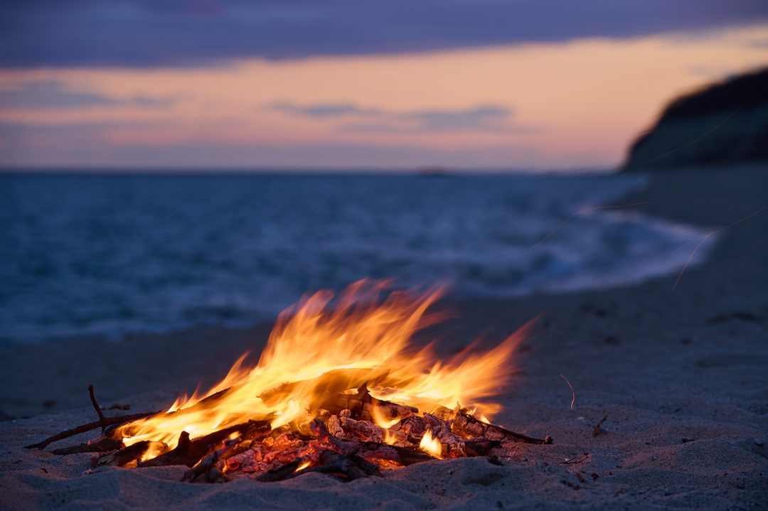A campfire on a beach at dusk